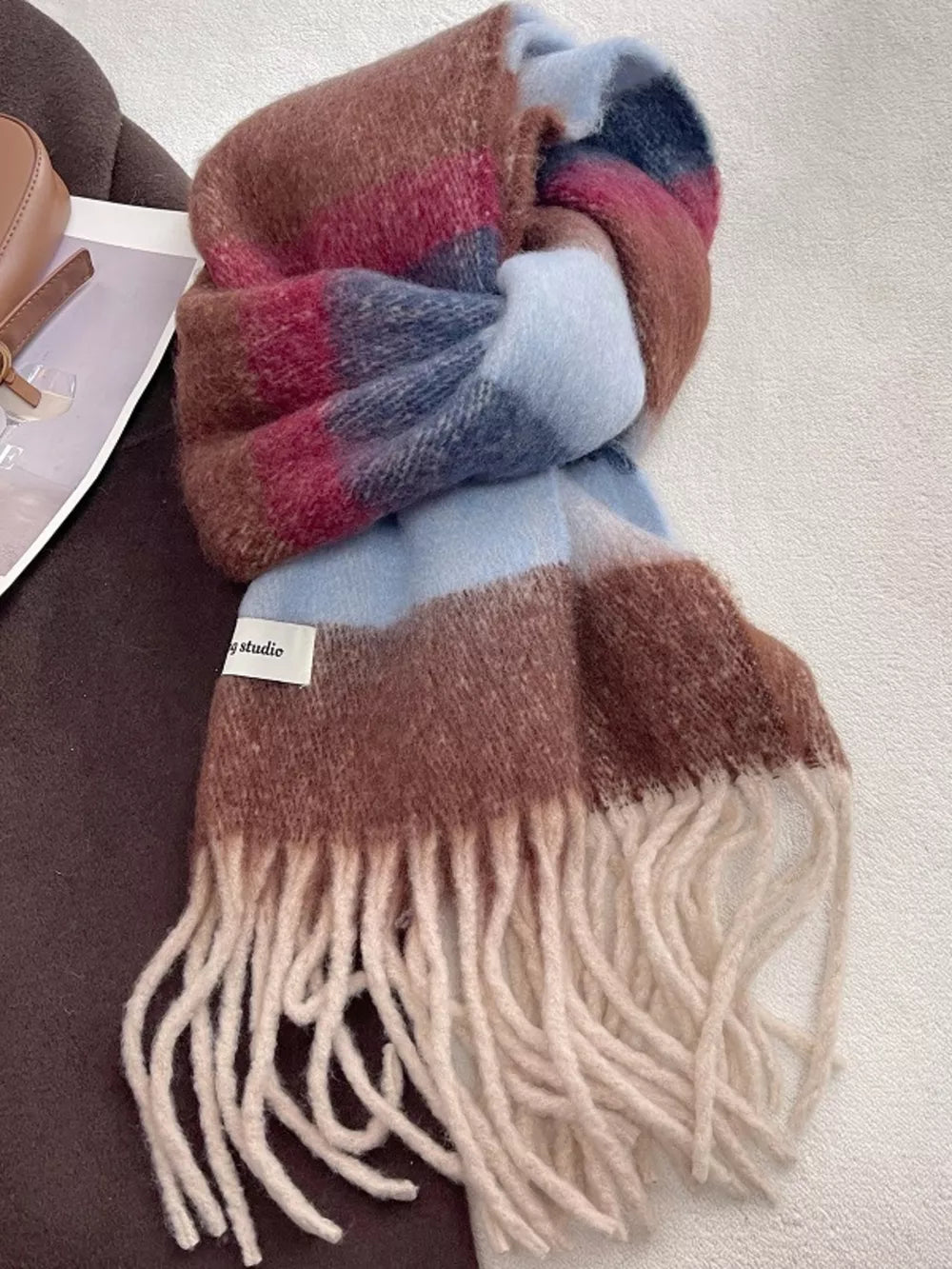 Plush multi-patterned scarf in brown, pink, blue, and cream with fringe detail.