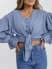 Light blue textured puff sleeve blouse with ruffled cuffs and tie front.