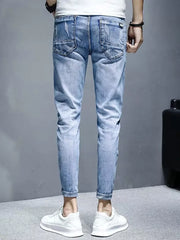 Men's light wash distressed slim fit jeans with rolled cuffs.