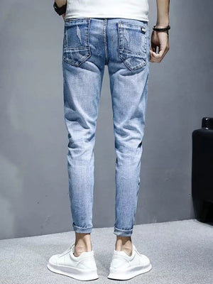 Men's light wash distressed slim fit jeans with rolled cuffs.