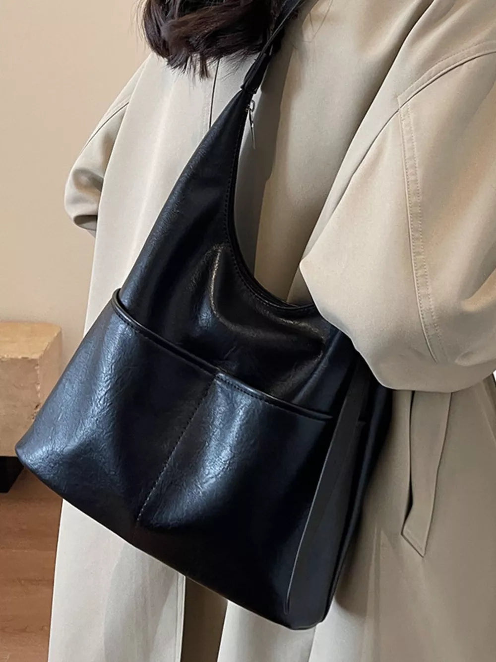 Black leather hobo shoulder bag with adjustable strap and front pockets.