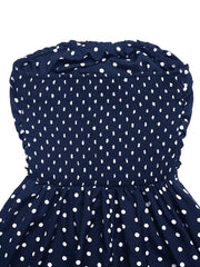 Navy polka dot strapless maxi dress with smocked bodice and ruffled neckline.