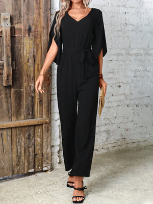 Black cape sleeve wrap jumpsuit with tie waist and wide legs.