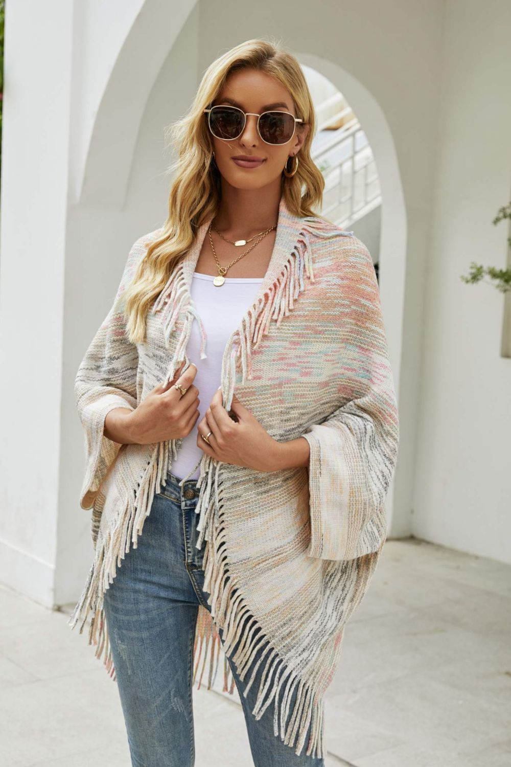 Textured stripe fringe cape in a multi-color knit with fringe trim.