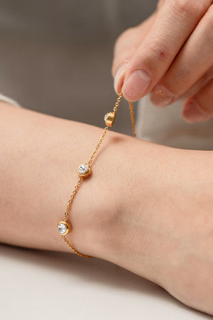 Gold chain bracelet with bezel-set cubic zirconia stones, close-up on wrist