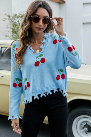 Light blue acrylic sweater with frayed v-neck and hem, featuring a red cherry motif pattern.