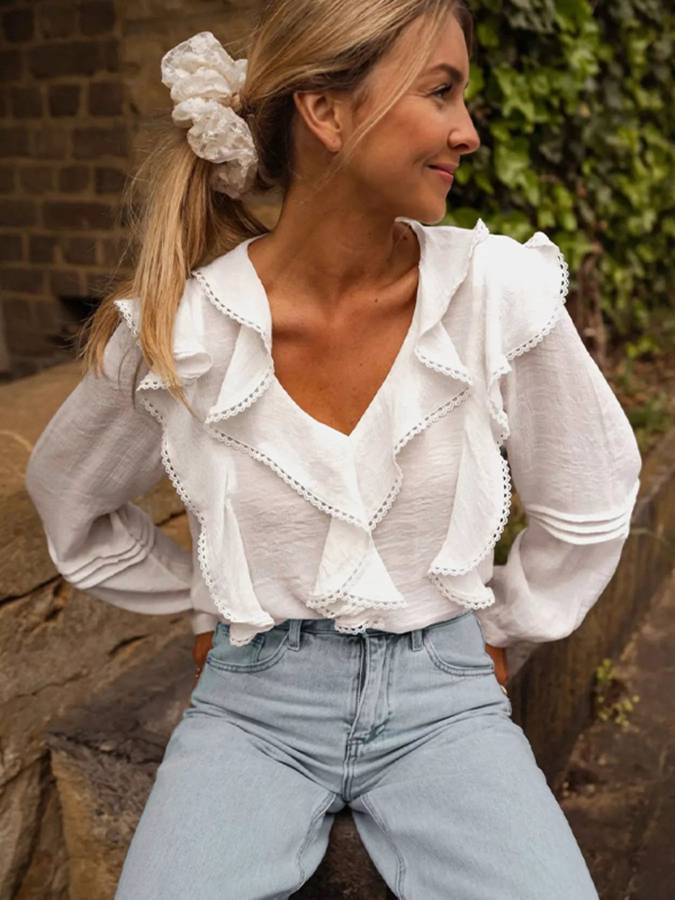 White lace ruffle v-neck blouse with long sleeves and lace trim details.