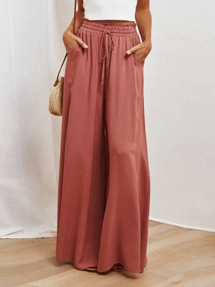 Gathered waist palazzo pants in orange-red with a drawstring and pockets.