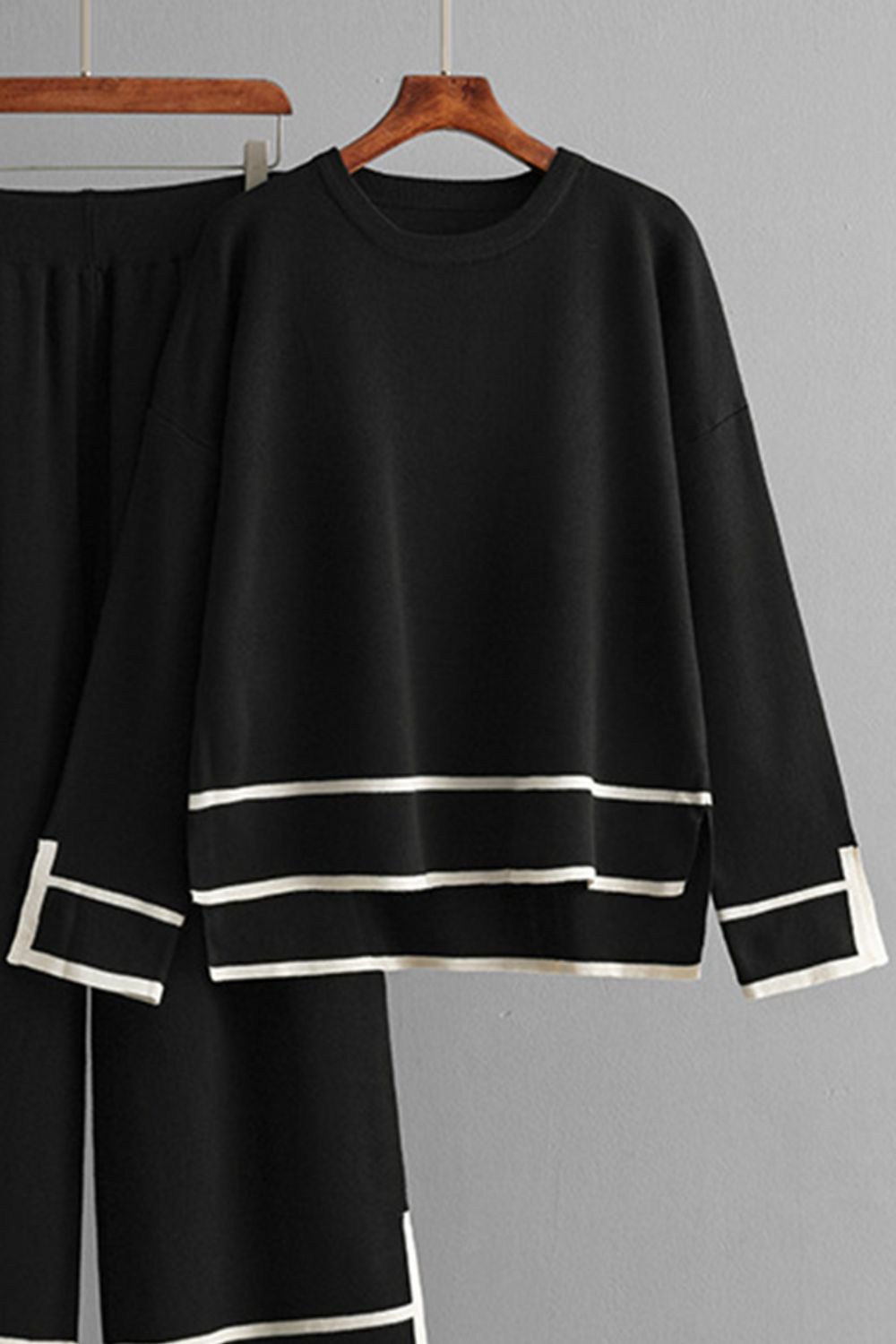 Black loungewear set with round neck top and sweater pants, featuring white stripe details.