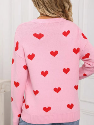 Pink acrylic knit sweater with a red heart print, crew neck, and long sleeves.