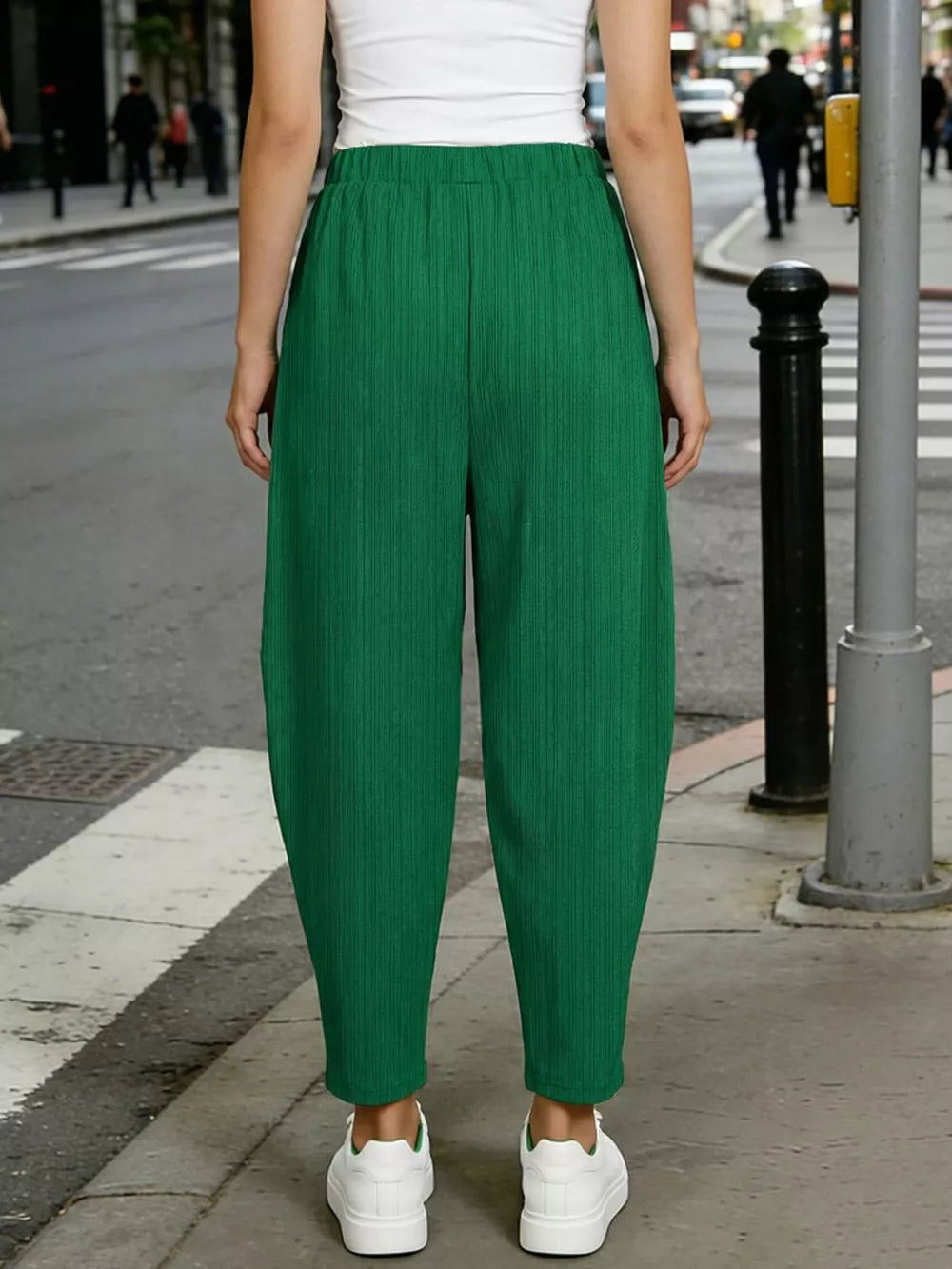 Dark green ribbed harem pants with elastic waist and pockets, styled with white sneakers.