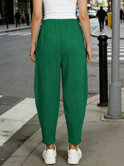 Dark green ribbed harem pants with elastic waist and pockets, styled with white sneakers.