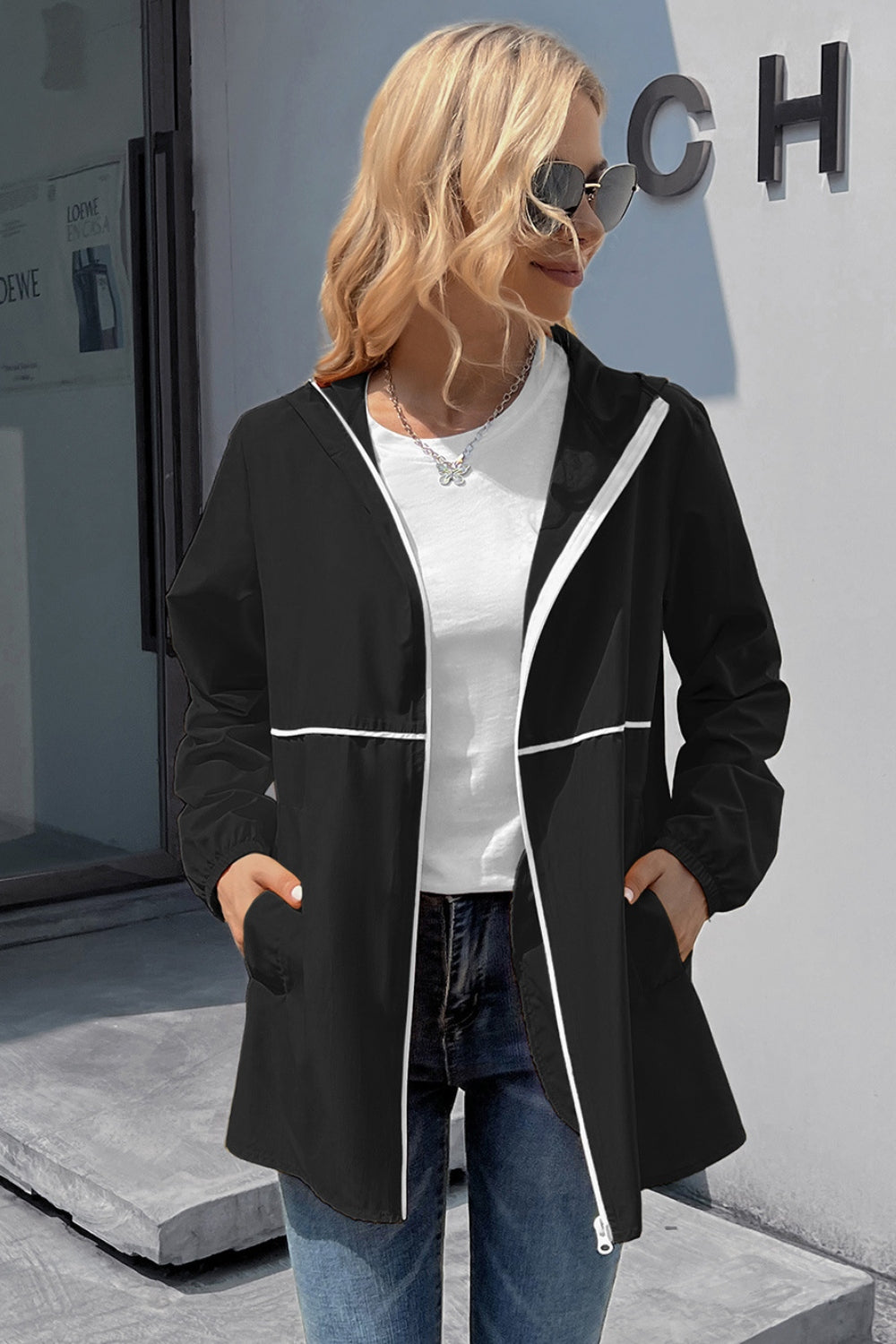 Black hooded rain coat with white trim and zipper detail.