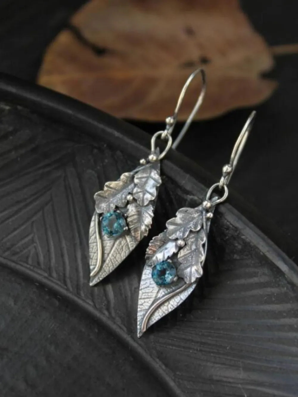 Textured leaf drop earrings with blue stones, boho style.