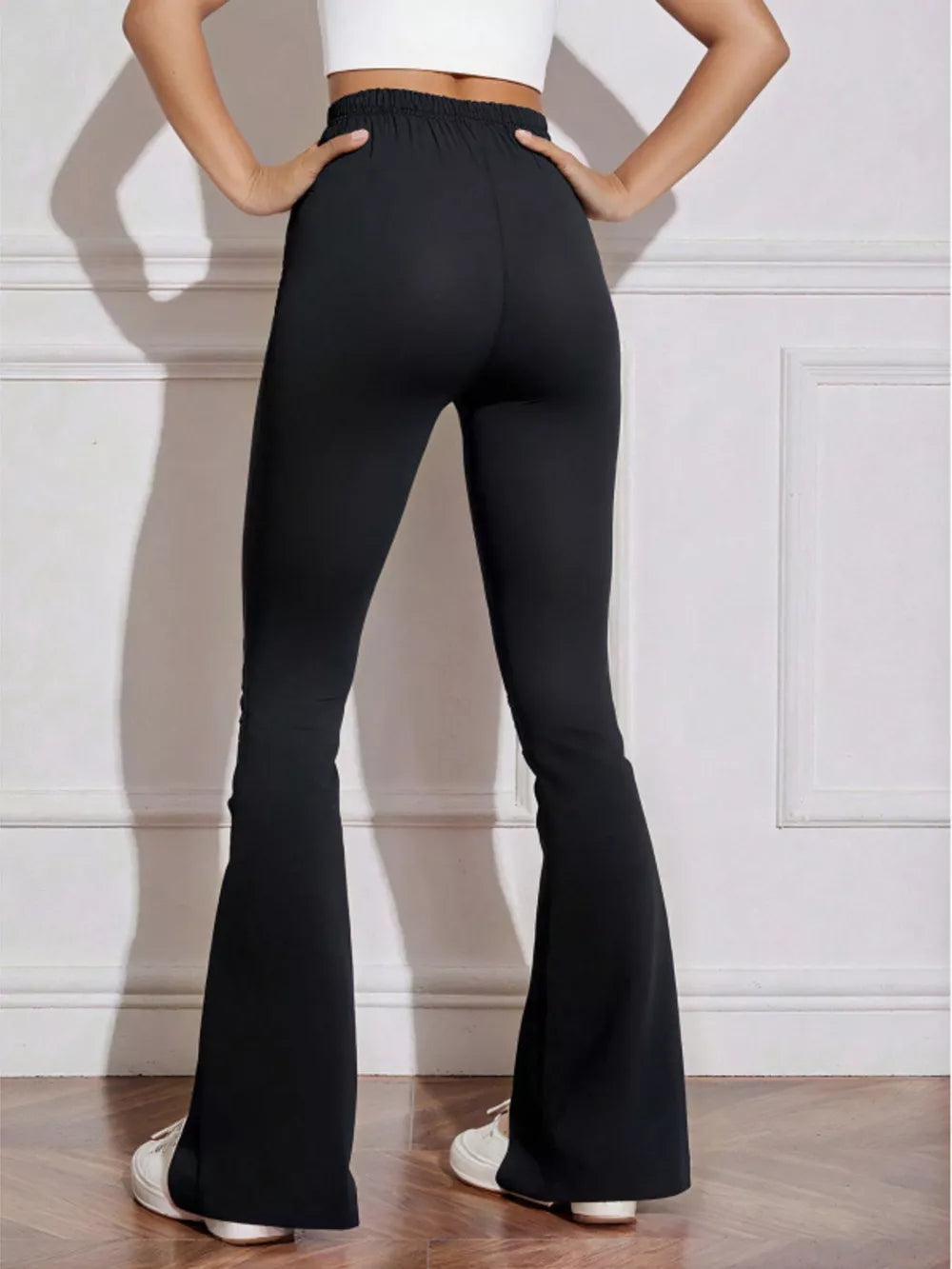 Black flared high-waist active pants with bow emblem detail.