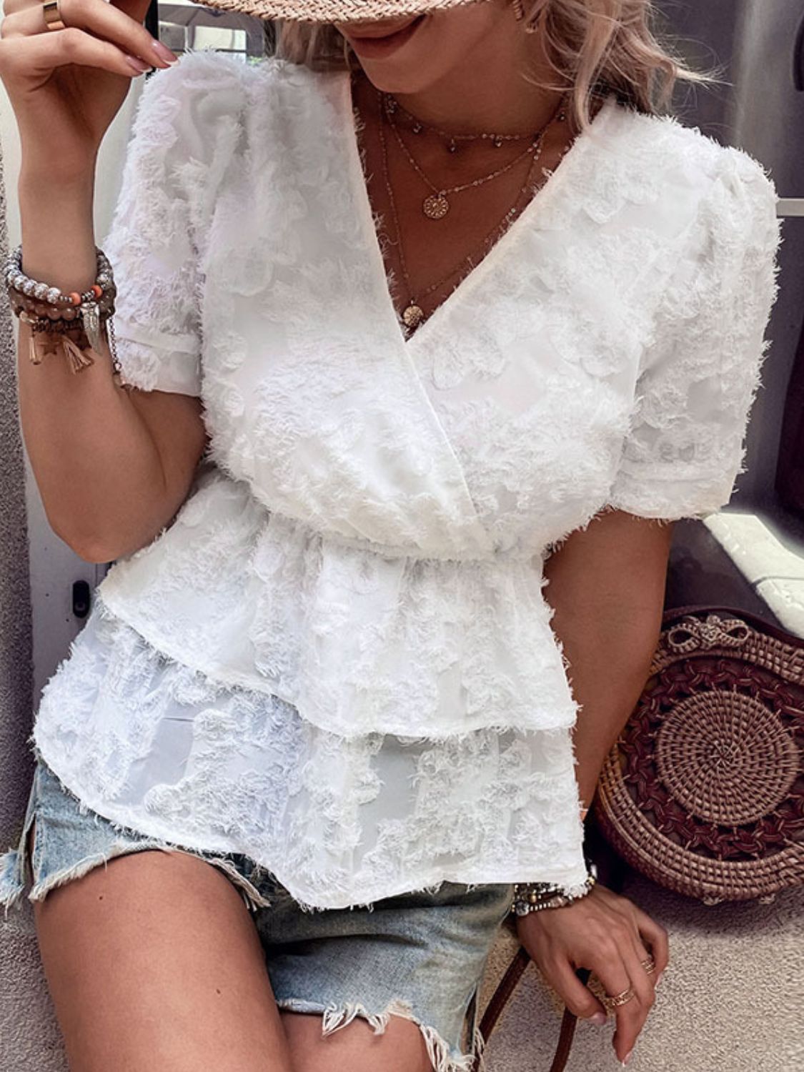 White textured surplice blouse with tiered peplum and short puff sleeves.