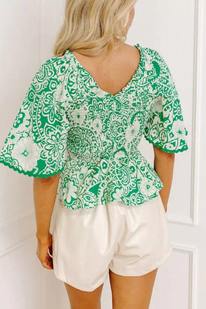 Green floral smocked v-neck polyester overshirt with ruffled sleeves.