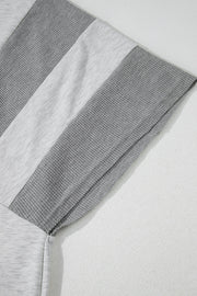 Colorblock waffle knit henley top in gray with contrast fabric panels and visible stitching detail.