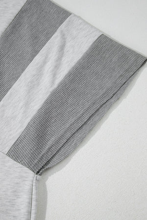 Colorblock waffle knit henley top in gray with contrast fabric panels and visible stitching detail.