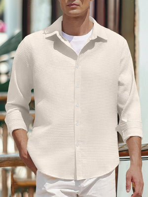 Men's white waffle knit button-up shirt with rolled sleeves.