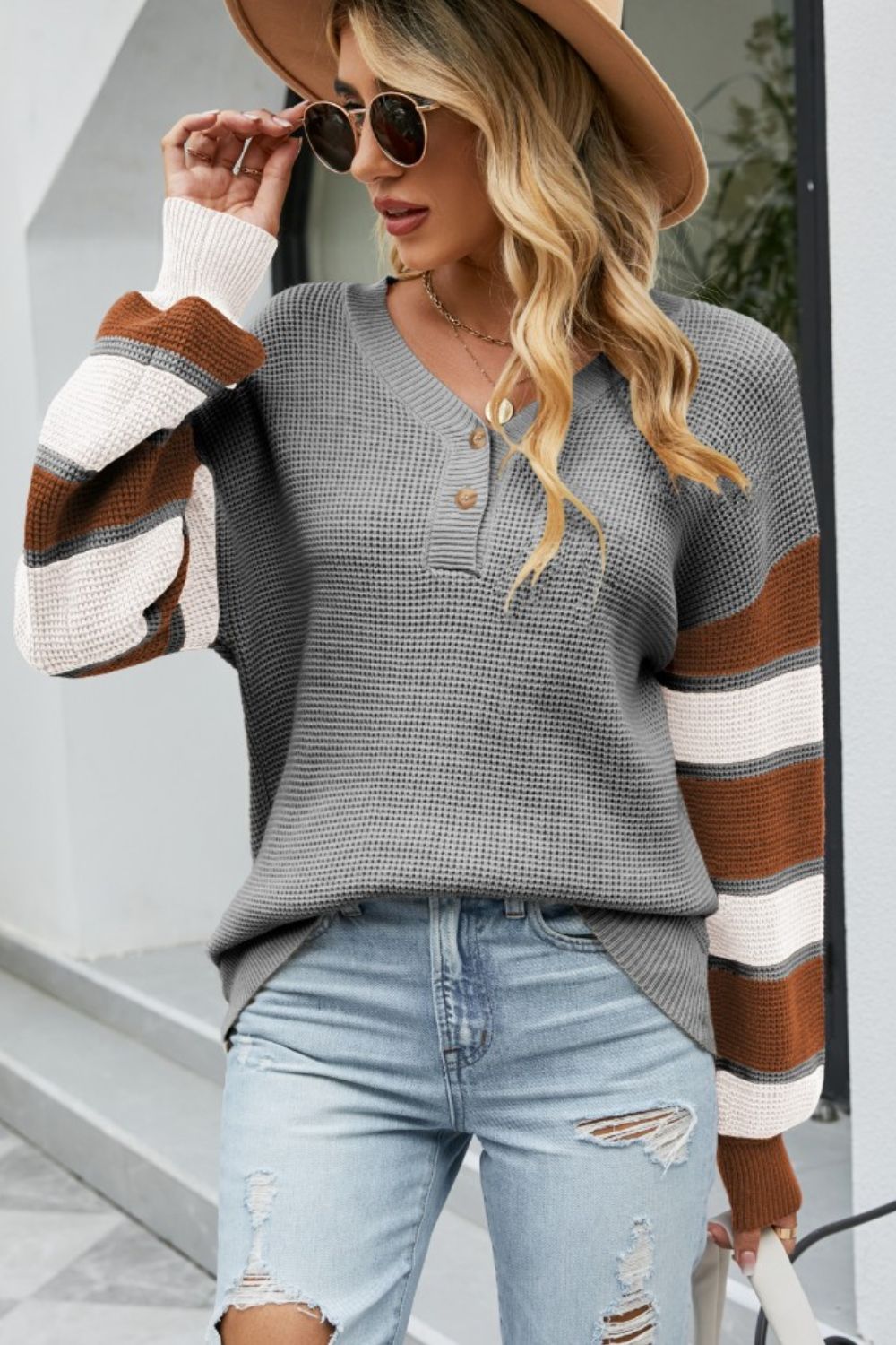 Waffle knit henley sweater in dark gray with striped sleeves in brown, white, and gray.