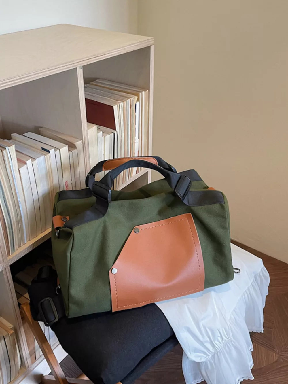 Green nylon crossbody bag with tan leather contrast pocket and strap detail.