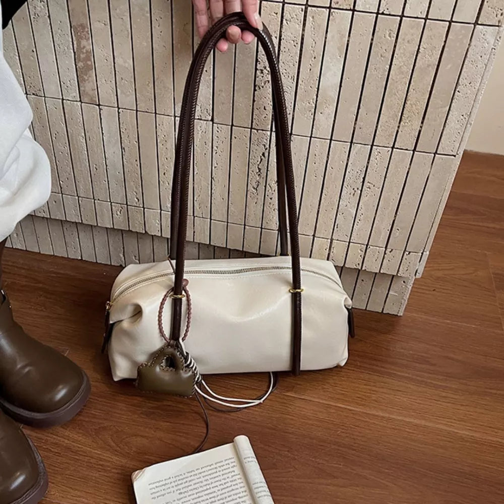Chic ivory pu leather shoulder bag with dark brown straps and a small charm.