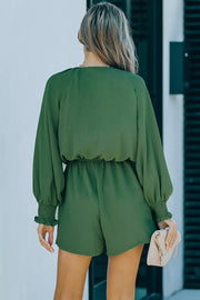Dark green tie knot puff sleeve romper with cinched waist and smocked cuffs.