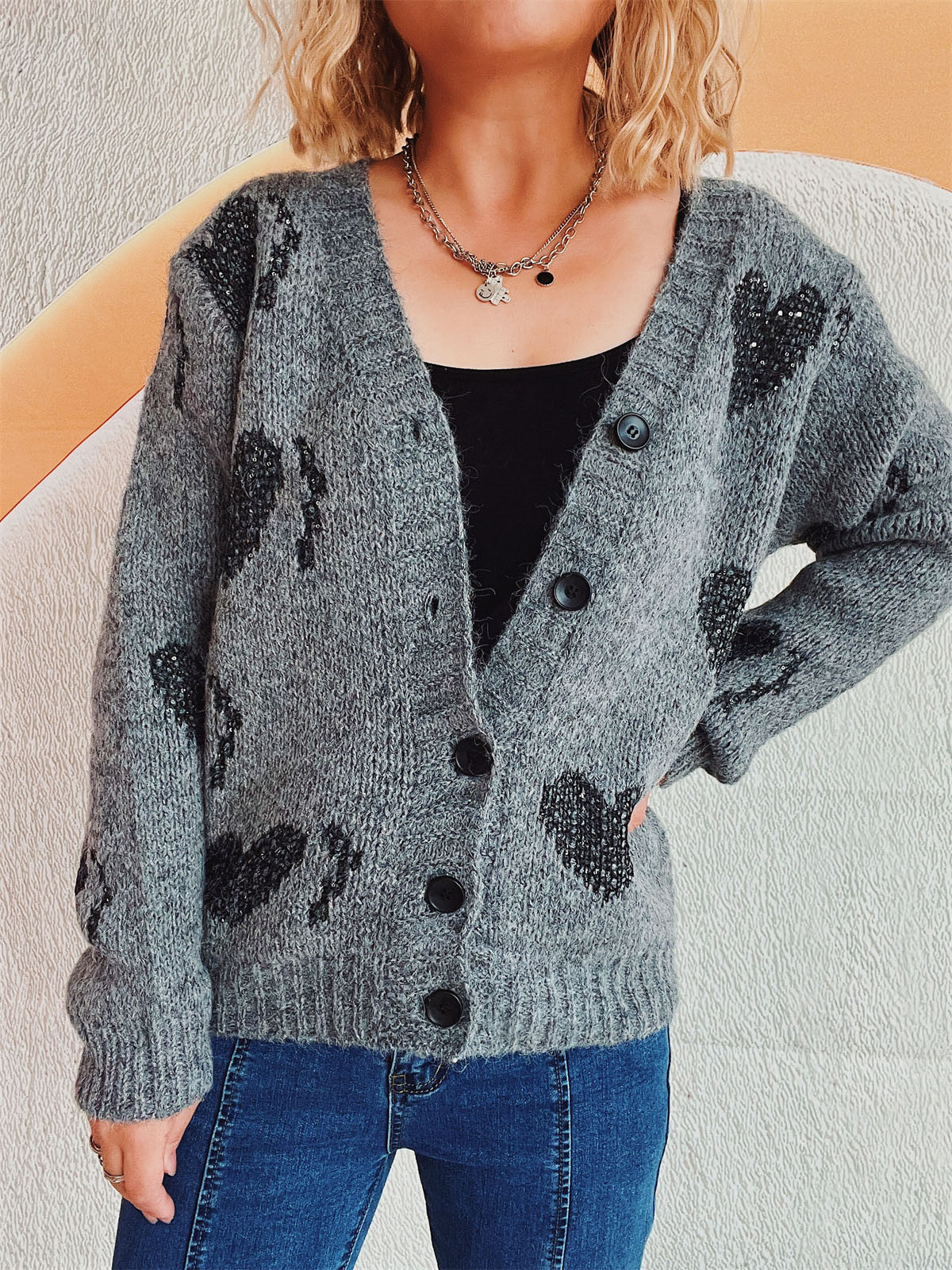 Dark gray acrylic knit cardigan with black heart motif and buttons.