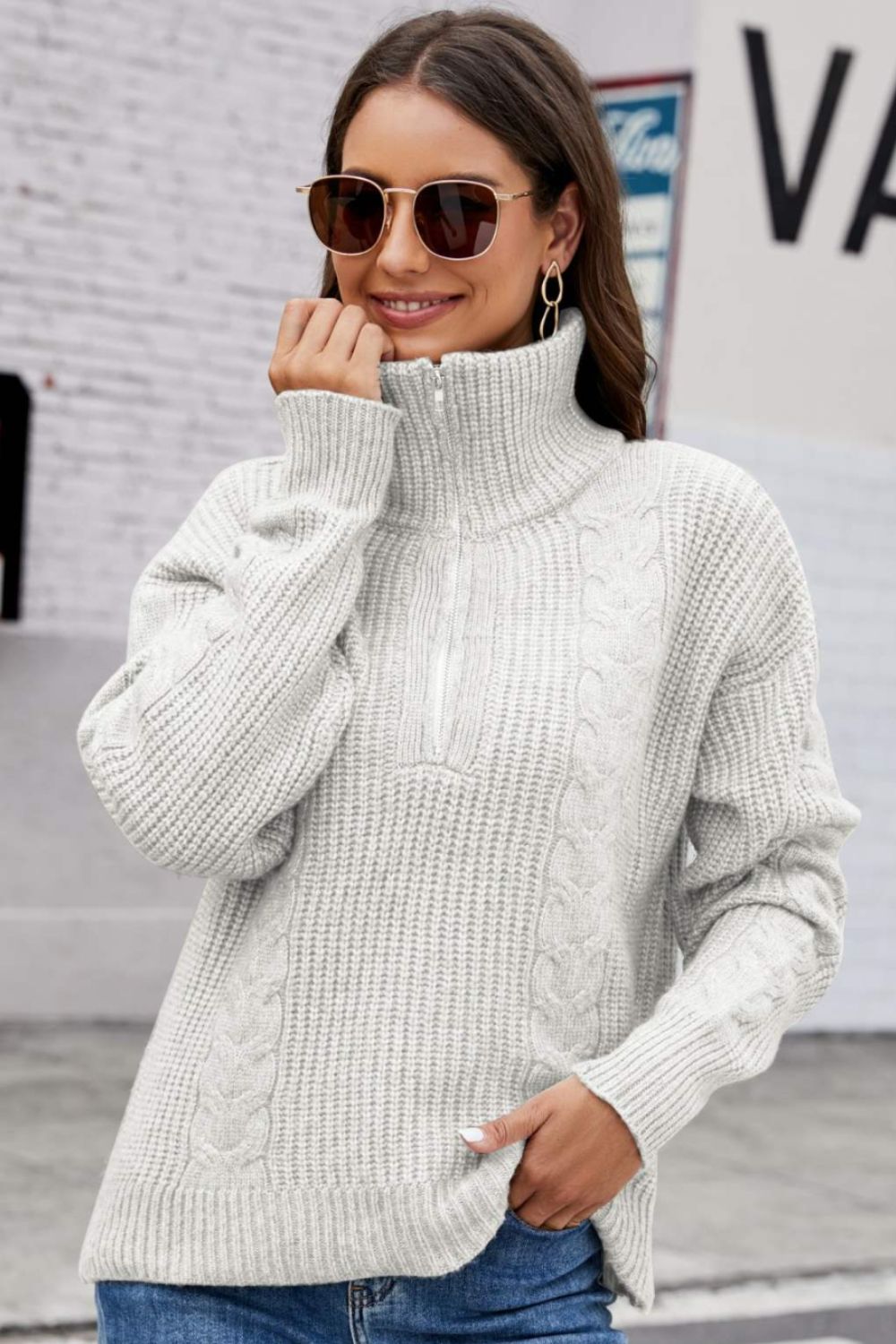 Gray cable knit zip-up sweater with a high collar and ribbed texture.