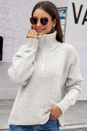 Gray cable knit zip-up sweater with a high collar and ribbed texture.