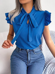 Royal blue pussy-bow blouse with ruffle sleeves and keyhole neckline, styled with jeans.