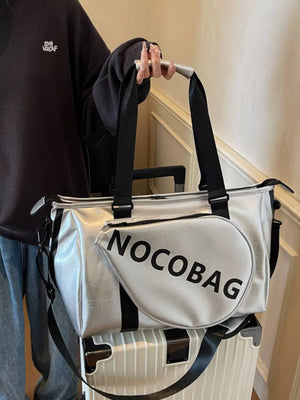 Silver leather duffel bag with black trim and "NOCOBAG" text, detachable strap.