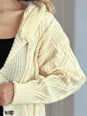 Beige cable knit hoodie with toggle closure and textured sleeves.