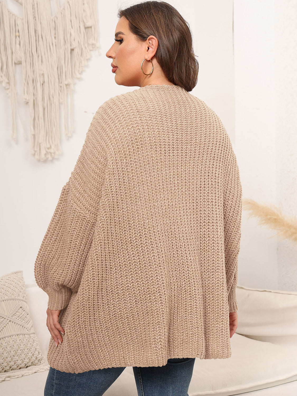 Chunky knit tan cardigan with balloon sleeves and open front, shown from the back.