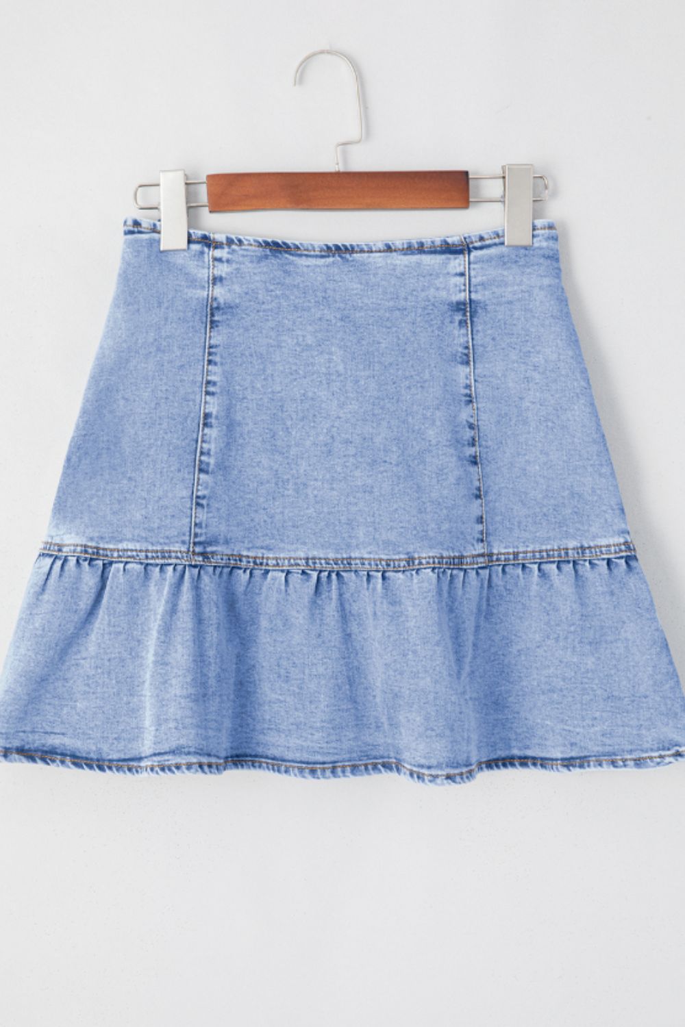 Asymmetrical denim mini skirt in medium wash with a ruffled hem.