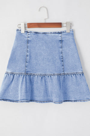 Asymmetrical denim mini skirt in medium wash with a ruffled hem.