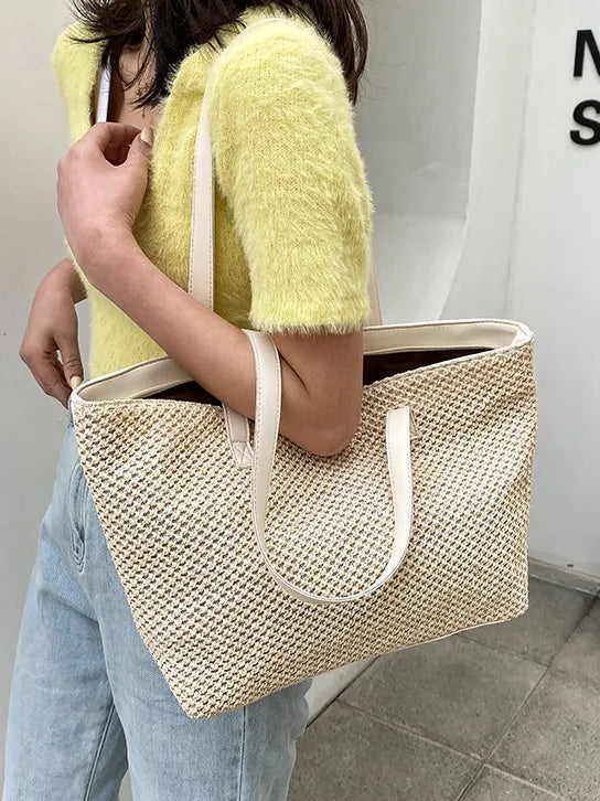 Textured straw shopper bag in beige with leather straps, open top.