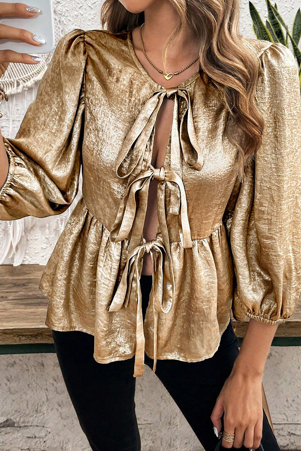 Gold peplum blouse with puff sleeves and a tie-front bow detail.