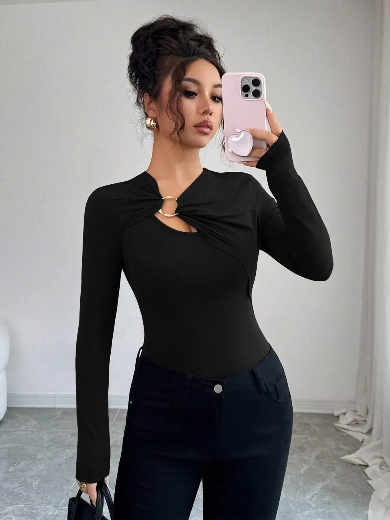 Black long-sleeve tee with asymmetrical cutout and gold ring detail.