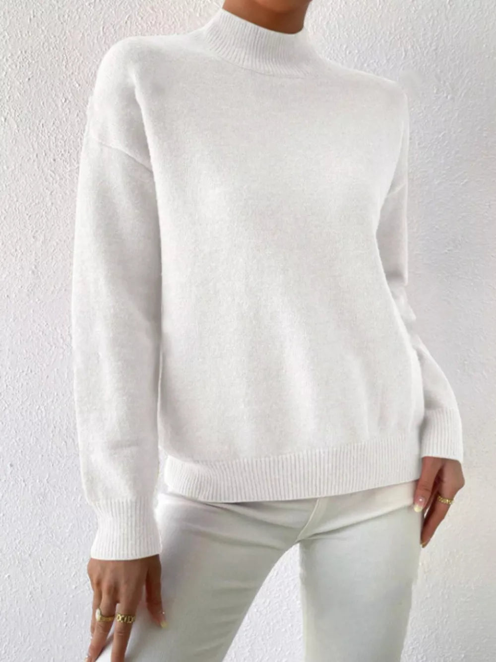 White mock neck knit sweater with dropped shoulders and ribbed cuffs and hem.