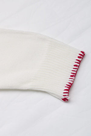White knit sweater sleeve with red contrast stitching detail