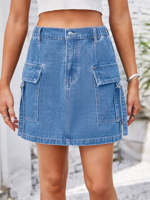 Denim mini skirt in medium wash with utility pockets and button closure.