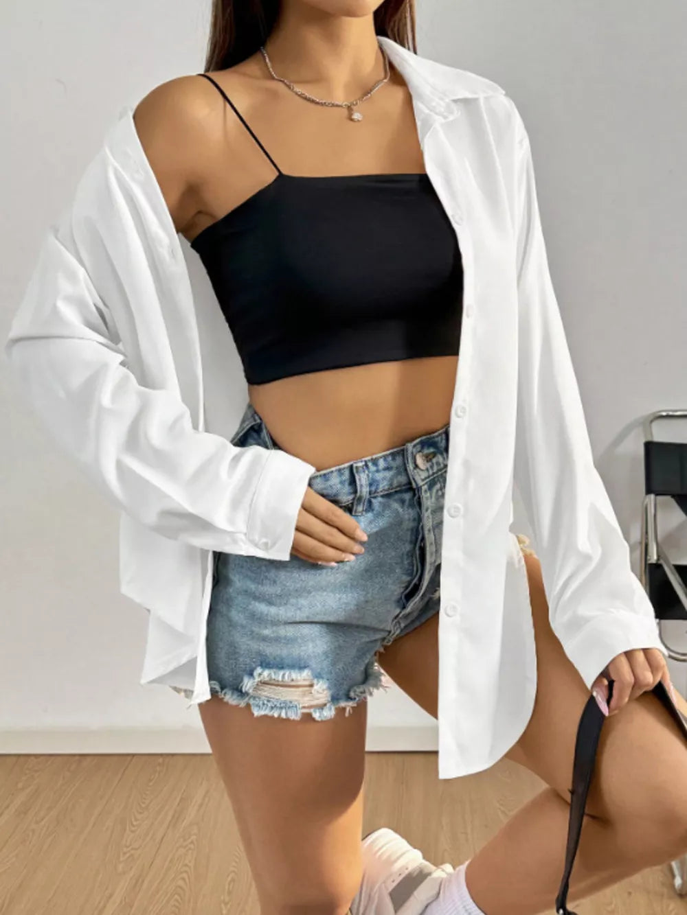White long sleeve button-up shirt worn open over a black cami and denim shorts