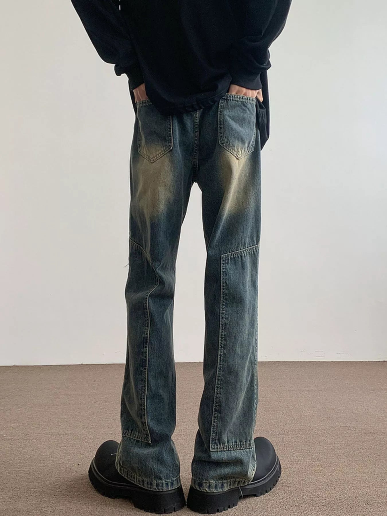 Men's blue vintage wash flare jeans with distressed detailing and paneling.