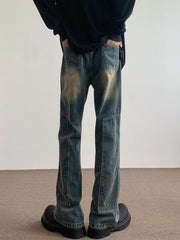 Men's blue vintage wash flare jeans with distressed detailing and paneling.