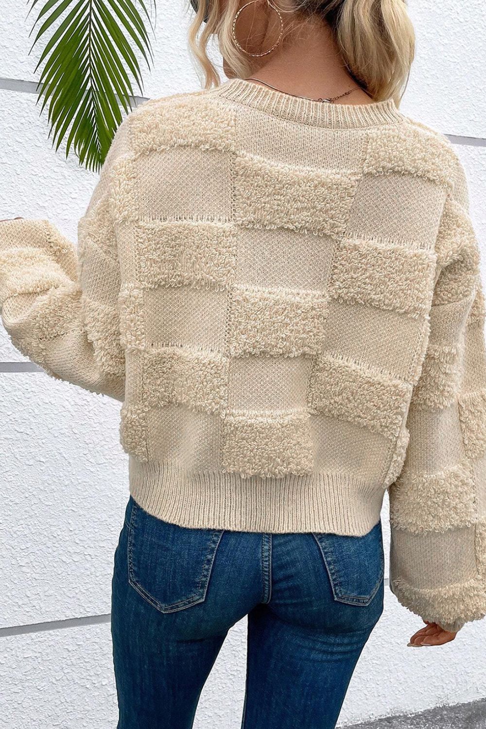 Beige checkerboard knit sweater with textured squares and crew neck.