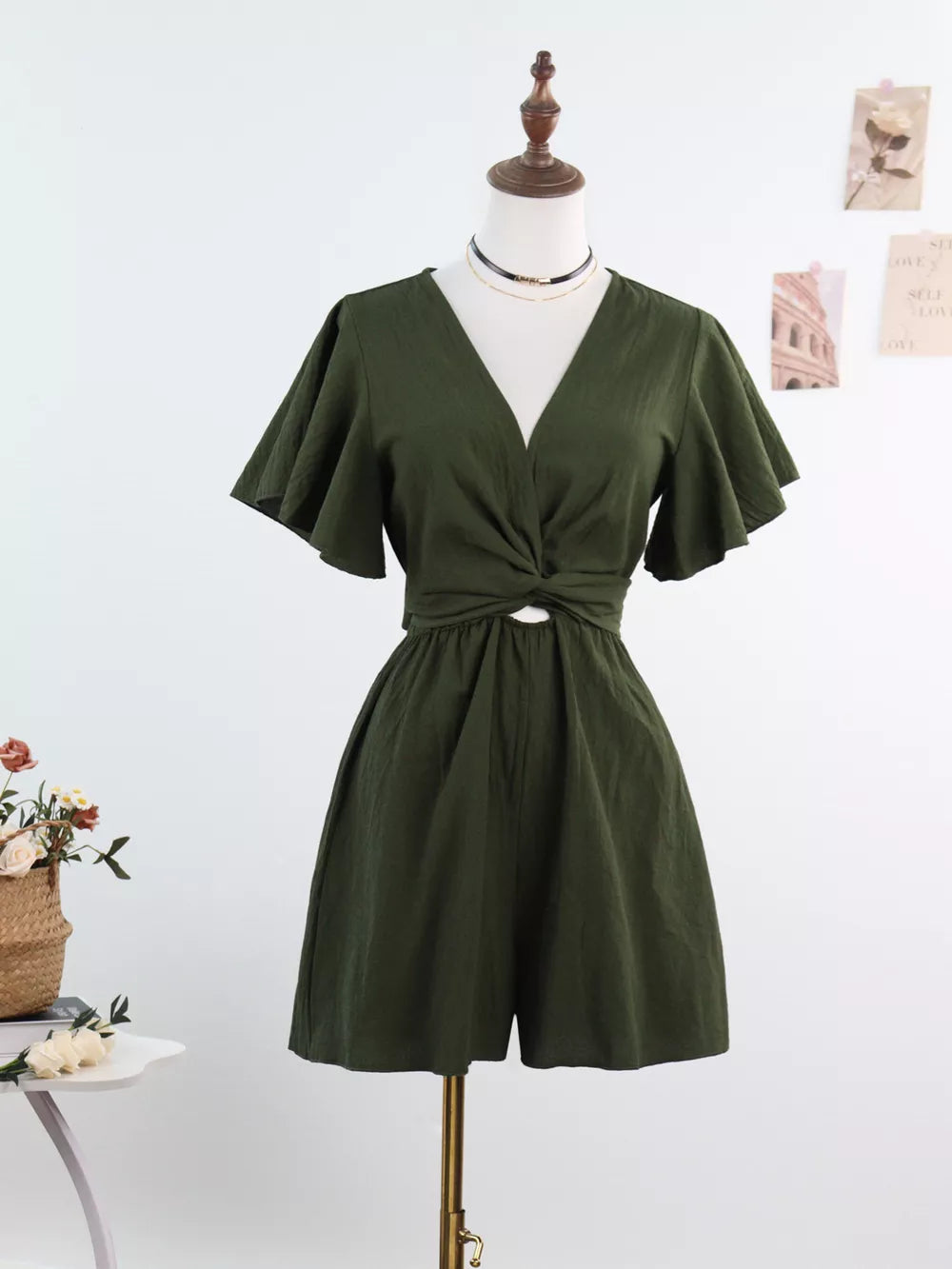 Olive green cotton romper with flutter sleeves, V-neck, and tie-waist detail.