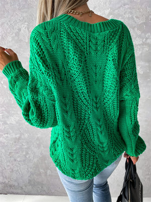 Green cable knit sweater with V-neck and relaxed fit, featuring intricate stitching details.