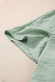 Sage oversized shirt romper with pockets and textured fabric detail.
